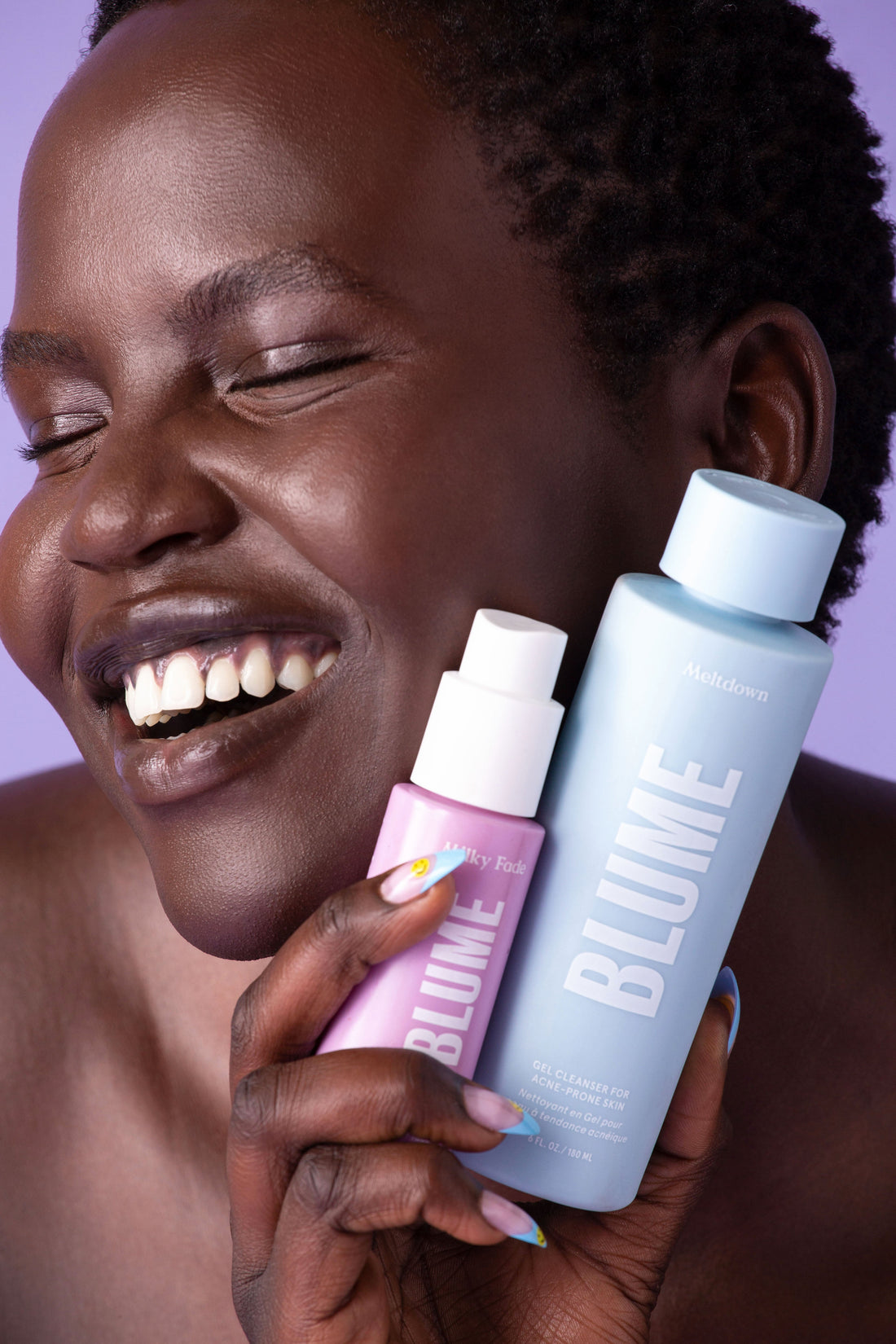 Smiling woman with glowing skin holding Blume Milky Fade dark spot serum and Blume Meltdown gel cleanser for acne-prone skin against a purple background.