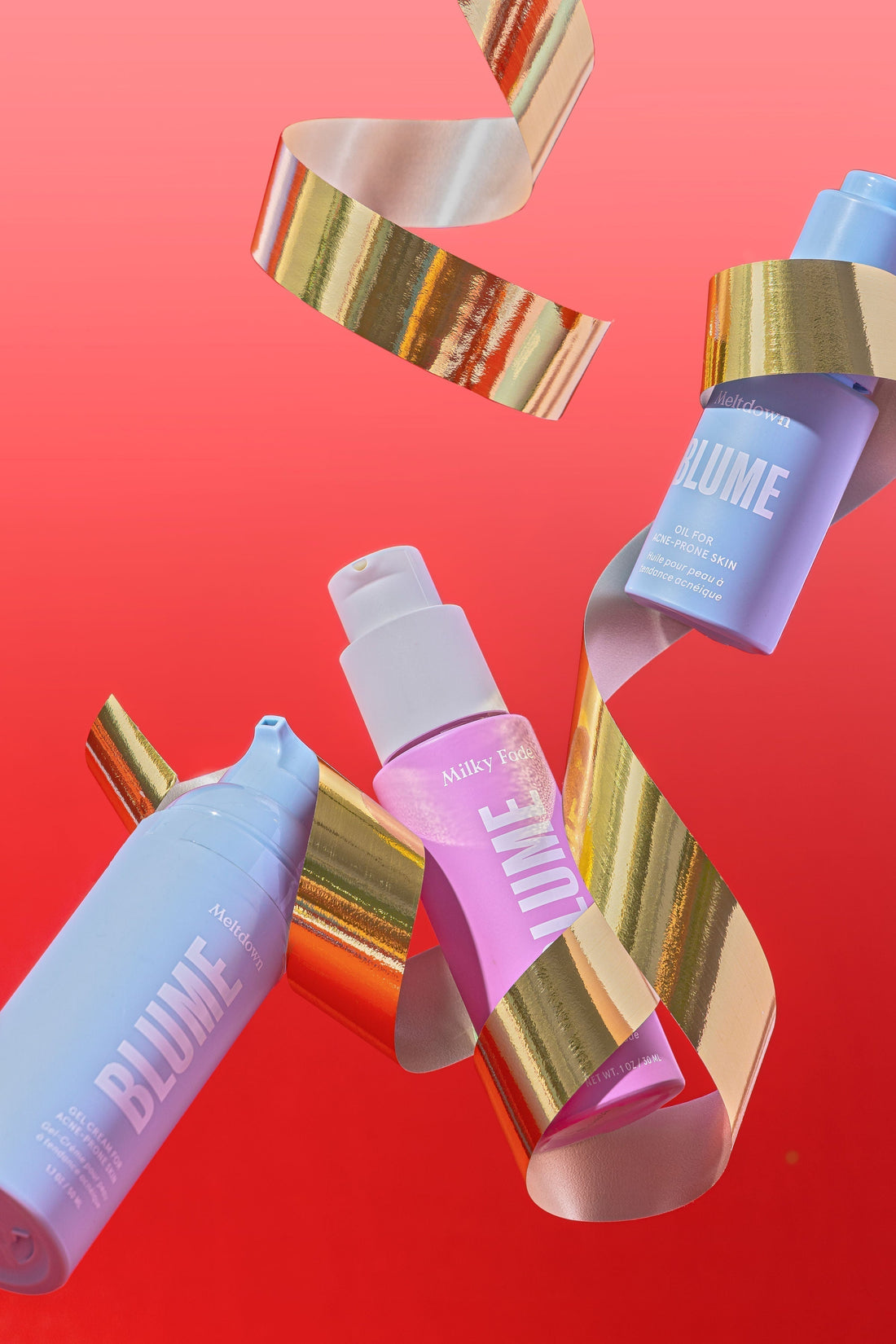 Blume Milky Fade and Meltdown bottles floating with metallic holiday ribbon against a red background.