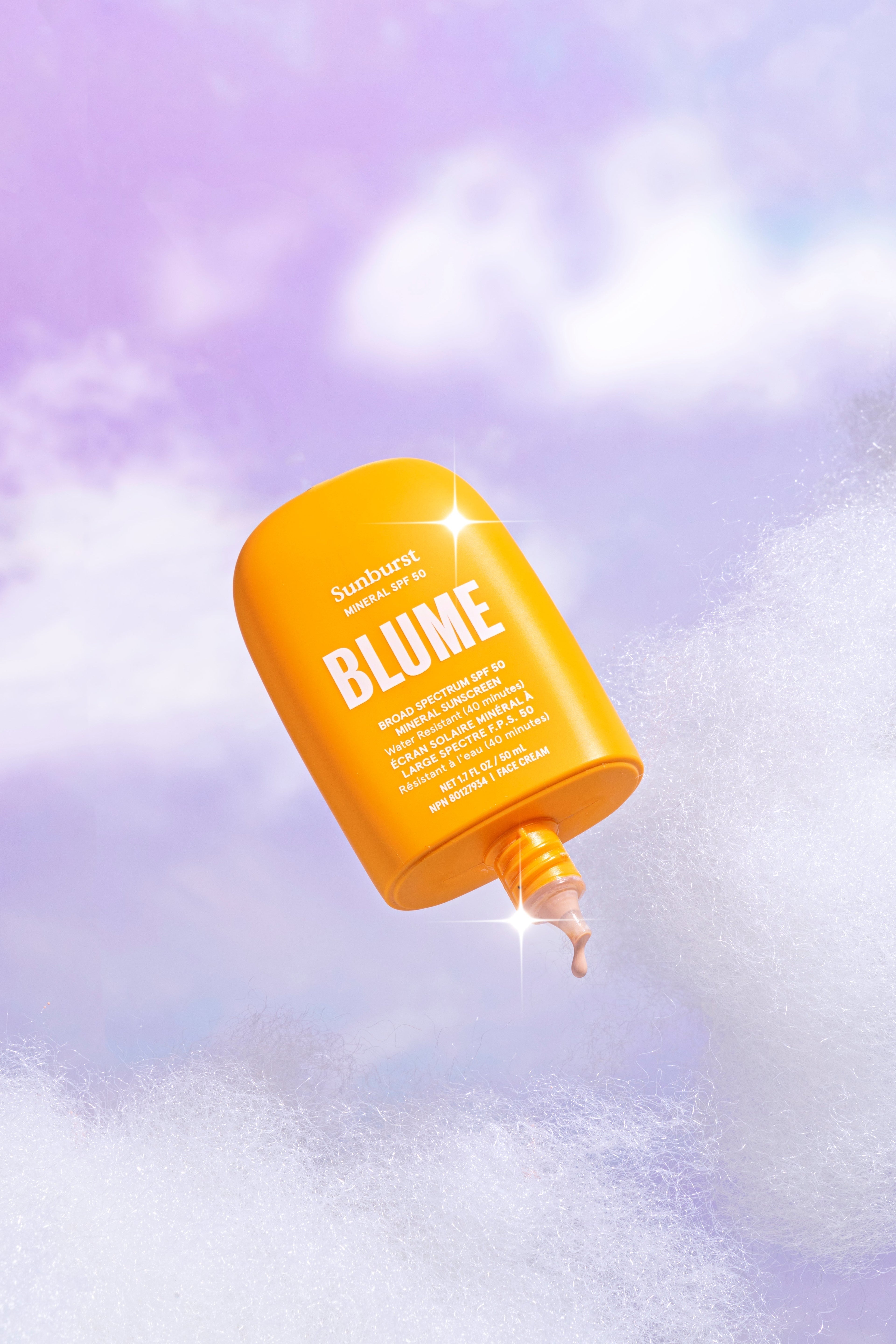 Blume Sunburst Mineral SPF 50 sunscreen bottle floating in a dreamy purple sky with clouds, dispensing a small amount of tinted sunscreen.