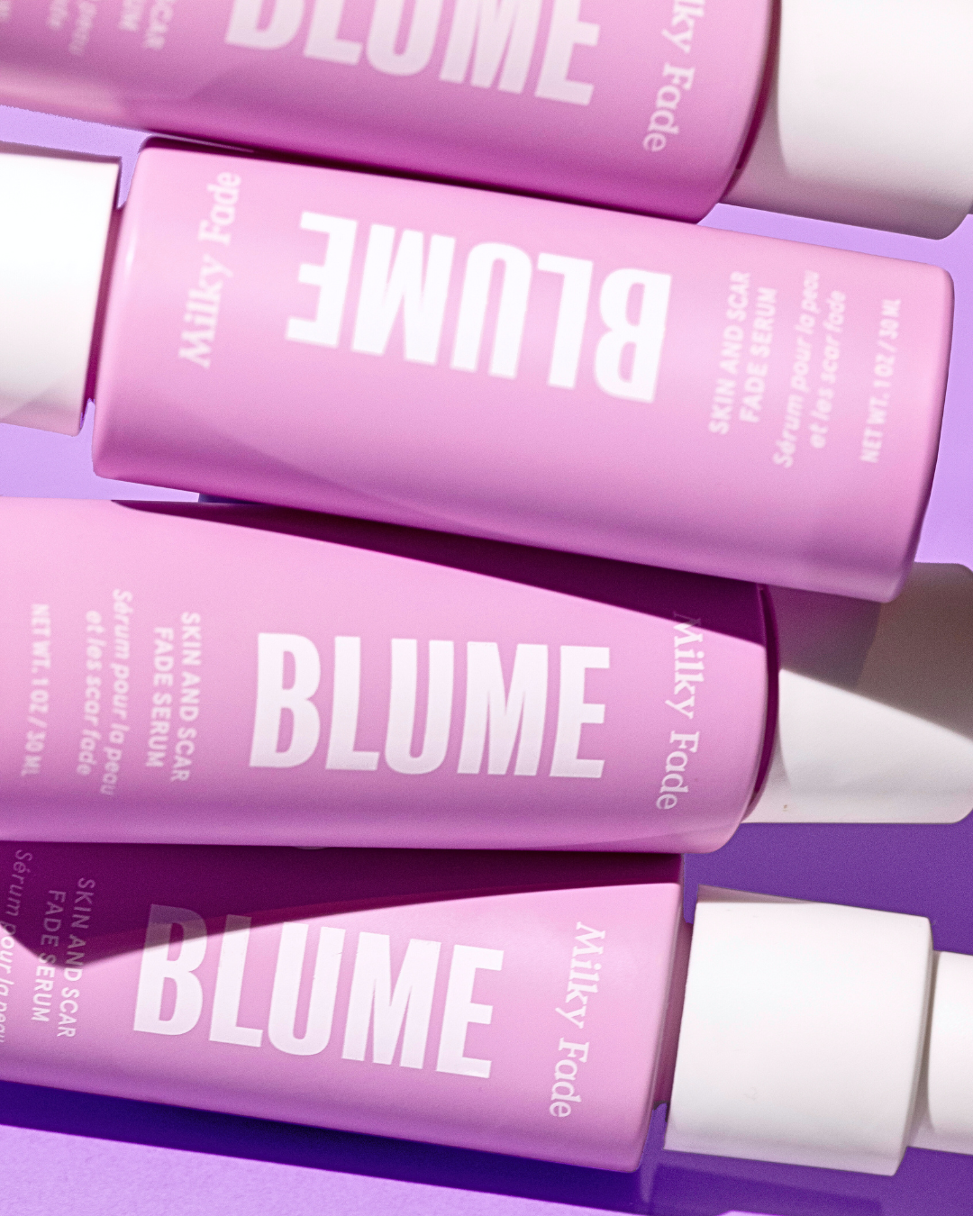 Overhead view of Blume Milky Fade serum bottles on pastel purple background