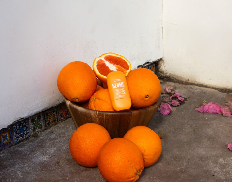 Blume Sunburst sunscreen surrounded by oranges, emphasizing vitamin C and sun protection benefits