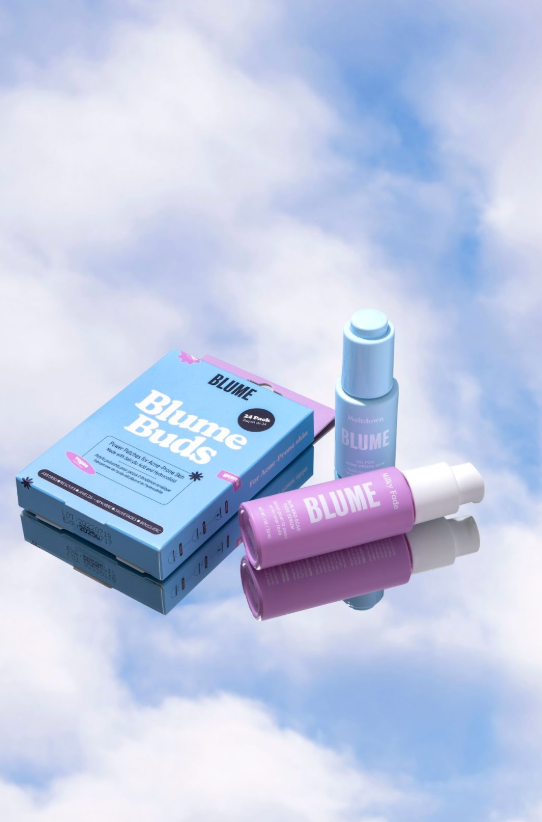 Blume skincare products arranged on a reflective surface against a cloudy sky background, including Blume Buds, Milky Fade serum, and Meltdown Acne Oil.
