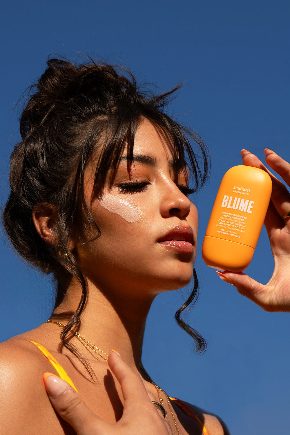 Sun-kissed model showing off Blume’s reef-safe, mineral SPF under blue sky