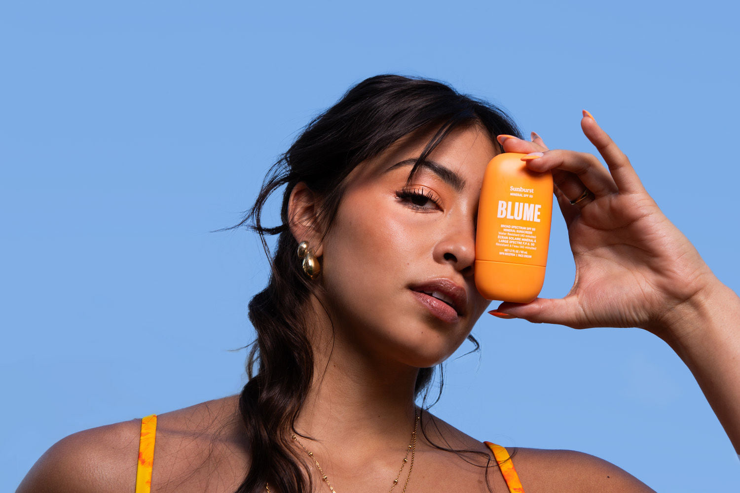 Model showcasing Blume’s mineral sunscreen with glowing skin and sun-kissed makeup