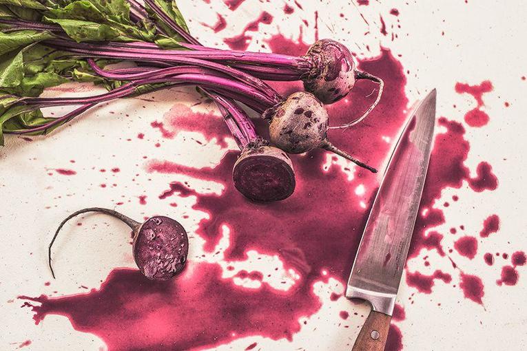 chopped beets next to a chef's knife with juices splattered